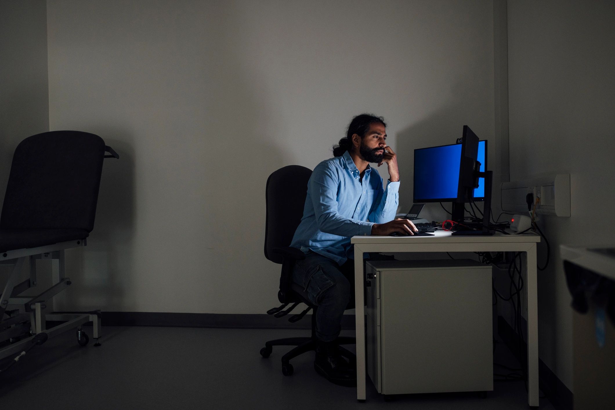 Analyst working at a computer in a dark room reviewing security data